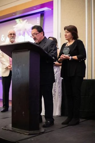 Photo of David De Luna accepting the award for his parents.